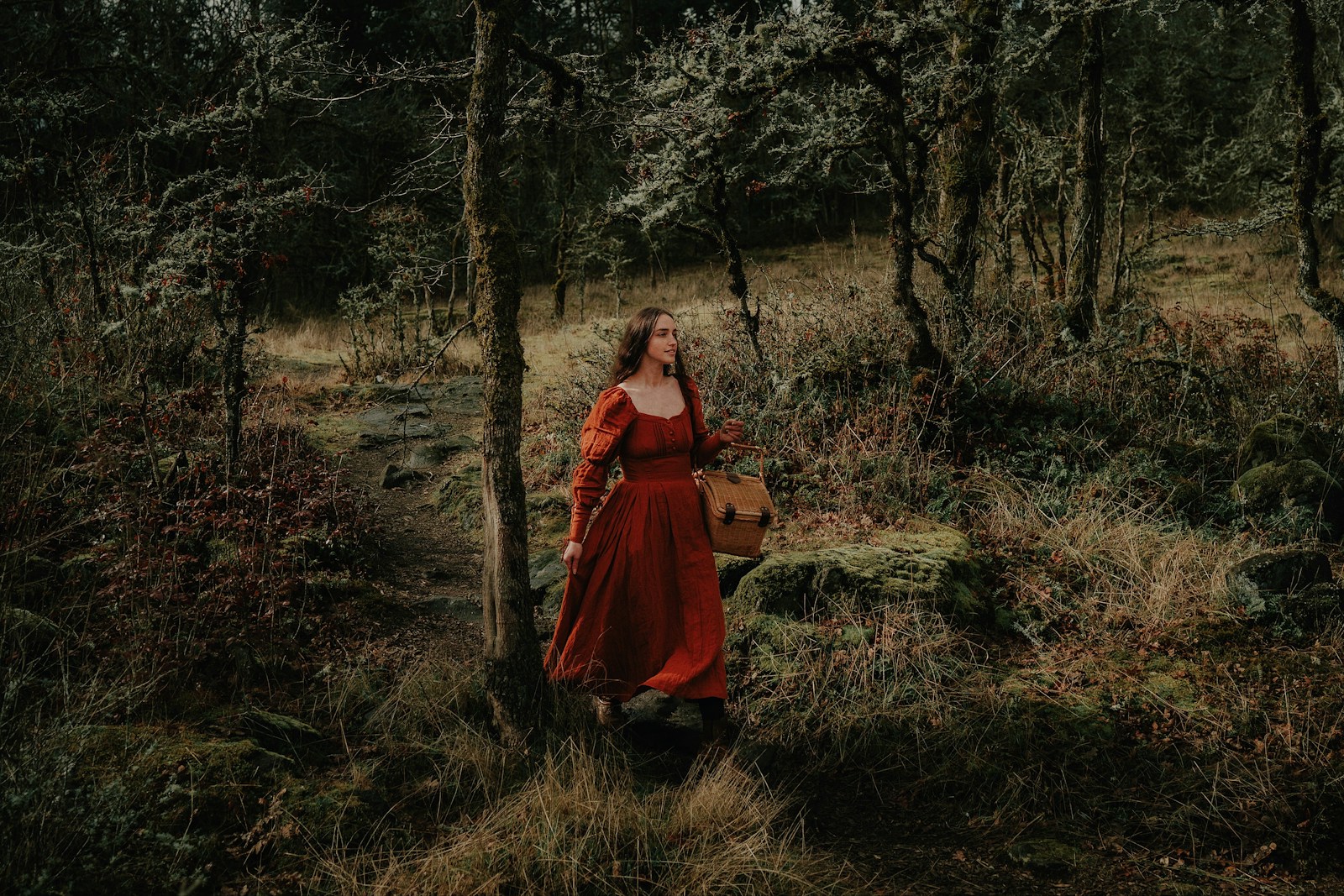 a woman in a red dress is walking through the woods